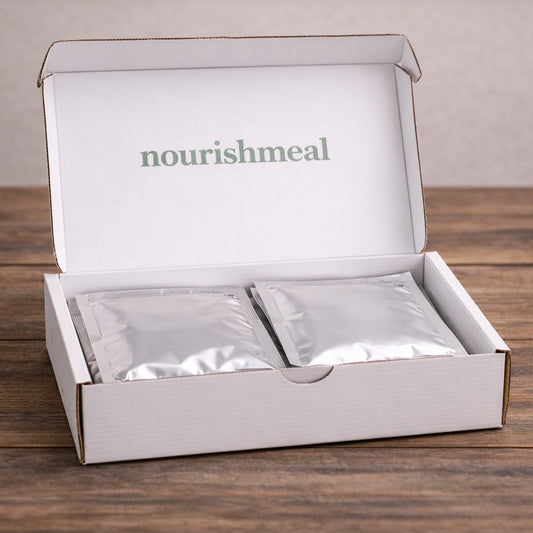 Open box of 'nourishmeal' with packets inside on a wooden surface.
